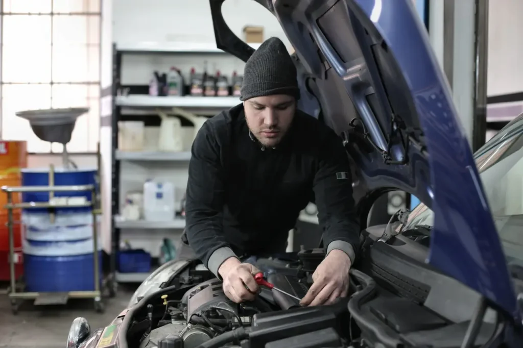 mechanic adjusting something in the engine of a car